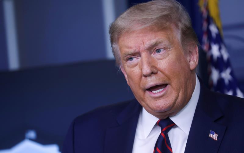 Donald Trump wearing a suit and tie: FILE PHOTO: U.S. President Trump speaks at coronavirus response task force briefing at the White House in Washington