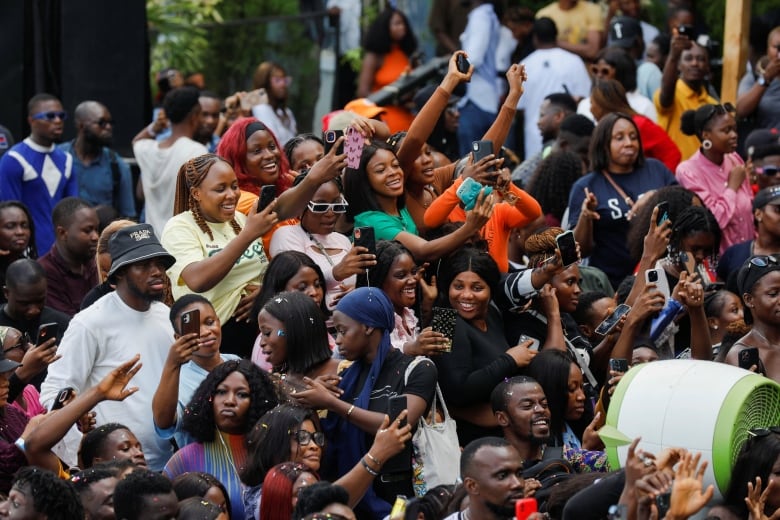 A crowd of smiling people holding up and looking at their phones